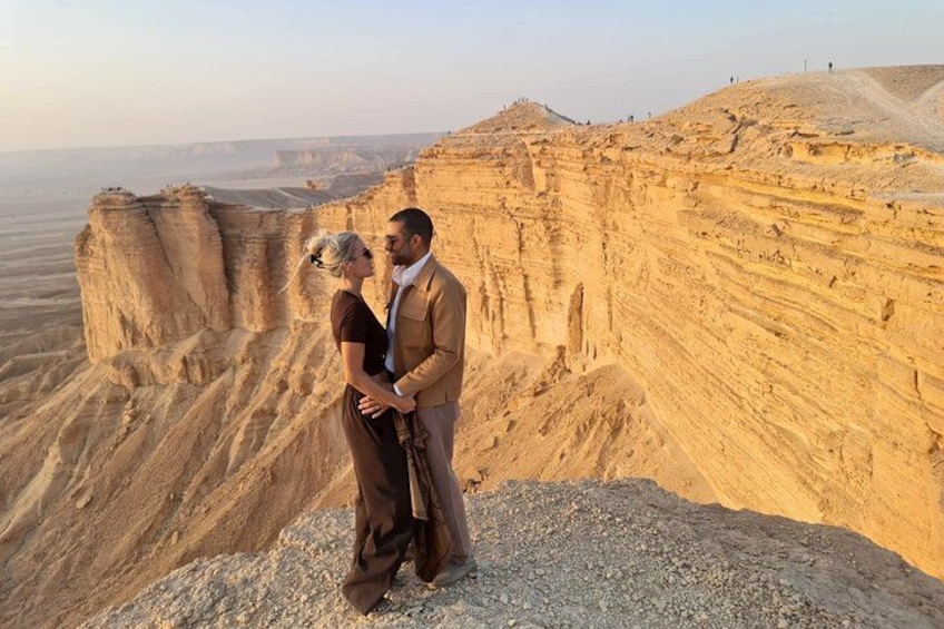 Una pareja parada en un promontorio rocoso, con un paisaje desértico al fondo. 4