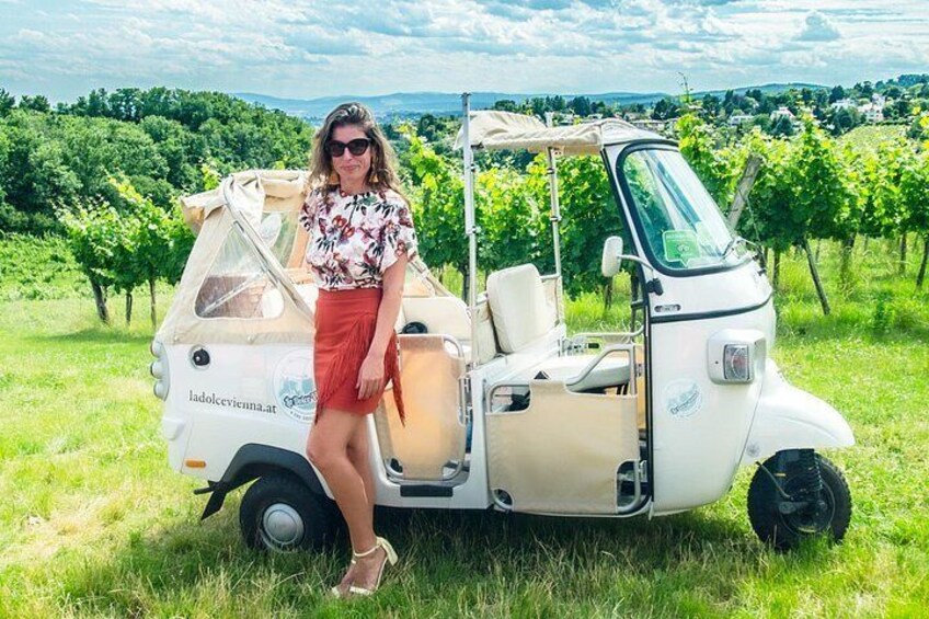 A woman standing next to a golf cart in a vineyard. 4
