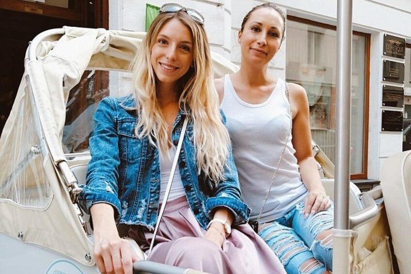 Two people sitting on a vehicle with a canopy, a pole, and a window. 3