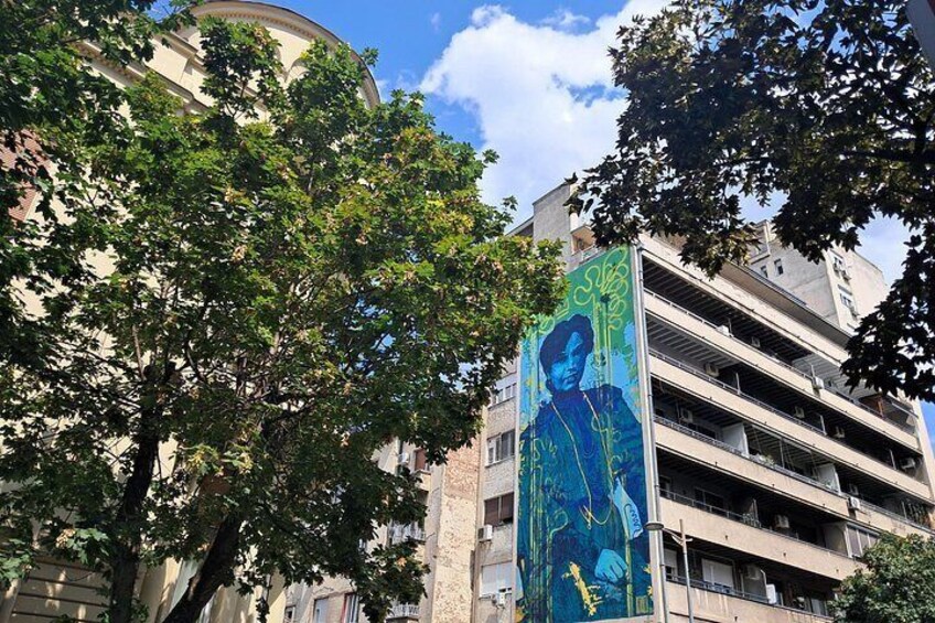 A building with a mural, trees, and a clear sky. 1