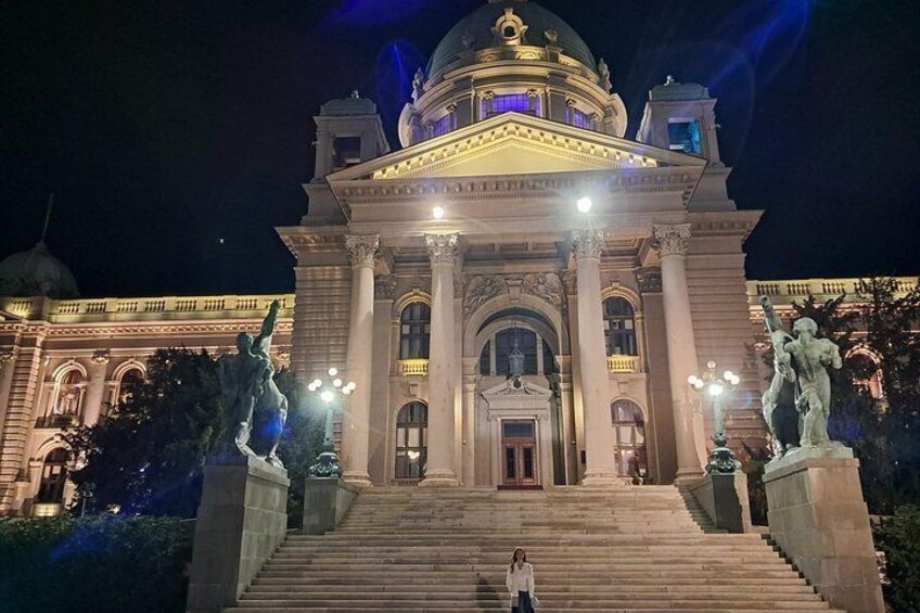 A grand building with a dome and statues at the entrance. 3