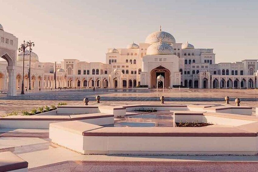 A large white building with domes and arches, surrounded by a courtyard with geometric patterns and a central water feature. 1