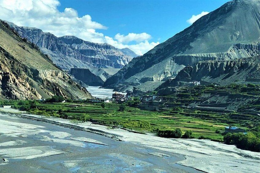 A mountainous landscape with terraced fields, a river, and a distant village. 5