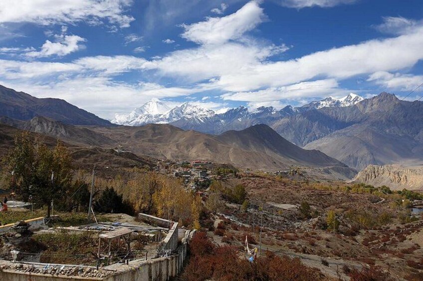 A mountainous landscape with a village, snow-capped peaks, and a clear sky. 2