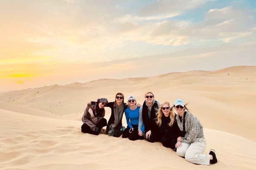 Un gruppo di persone seduto sulle dune di sabbia al tramonto. 2