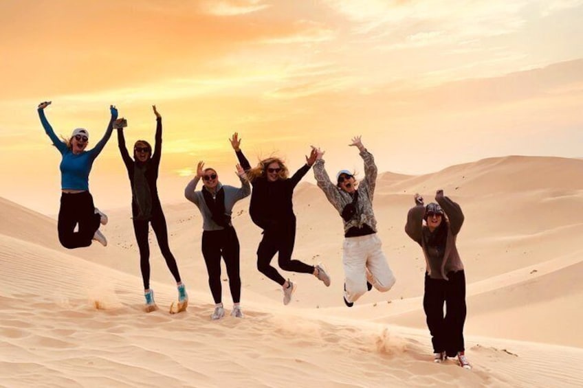 Un gruppo di persone salta nel deserto al tramonto. 3