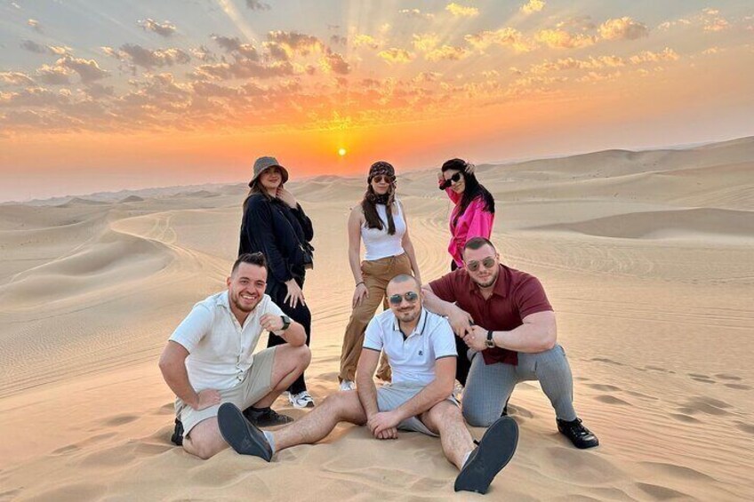 Un gruppo di persone sedute sulle dune di sabbia al tramonto. 1