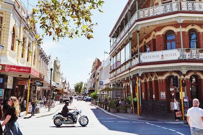 A street with a motorcyclist, buildings, and a hotel. 1