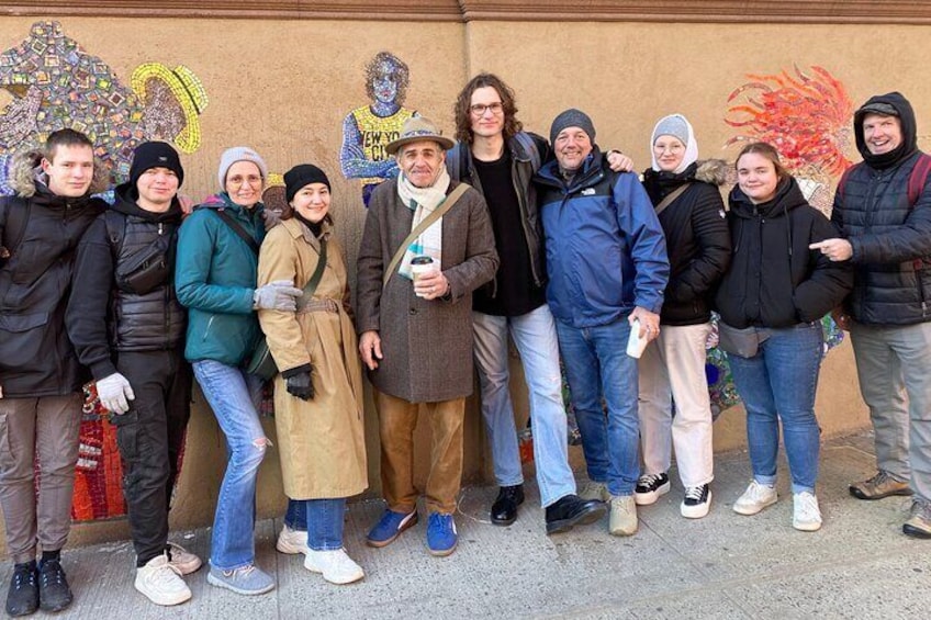 A group of people standing in a line outdoors, some wearing winter clothing. 4