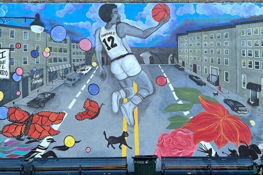 A mural of a basketball player in mid-air, a city street, and a cat. 5
