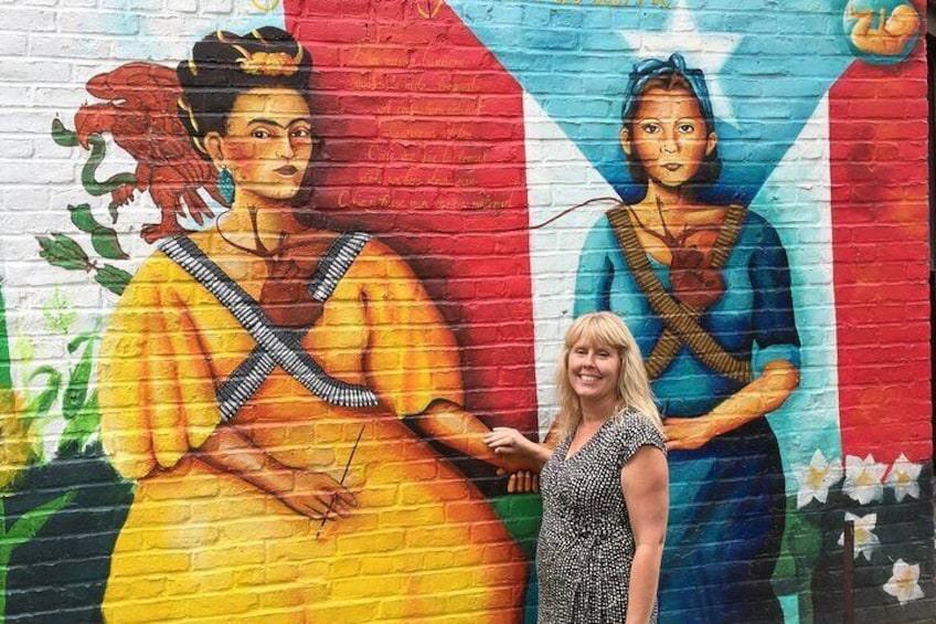 A mural with two figures, one in yellow and one in blue, on a brick wall. 3