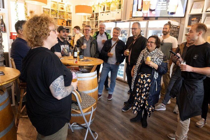 A group of people in a bar setting with wooden barrels and shelves of bottles. 2