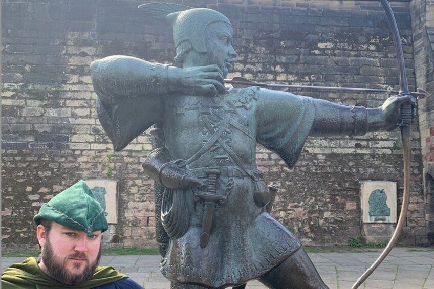 A statue of a figure in armor holding a bow, with a brick wall in the background. 2