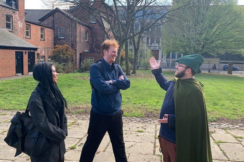 Three people standing on a sidewalk with buildings and trees in the background. 3