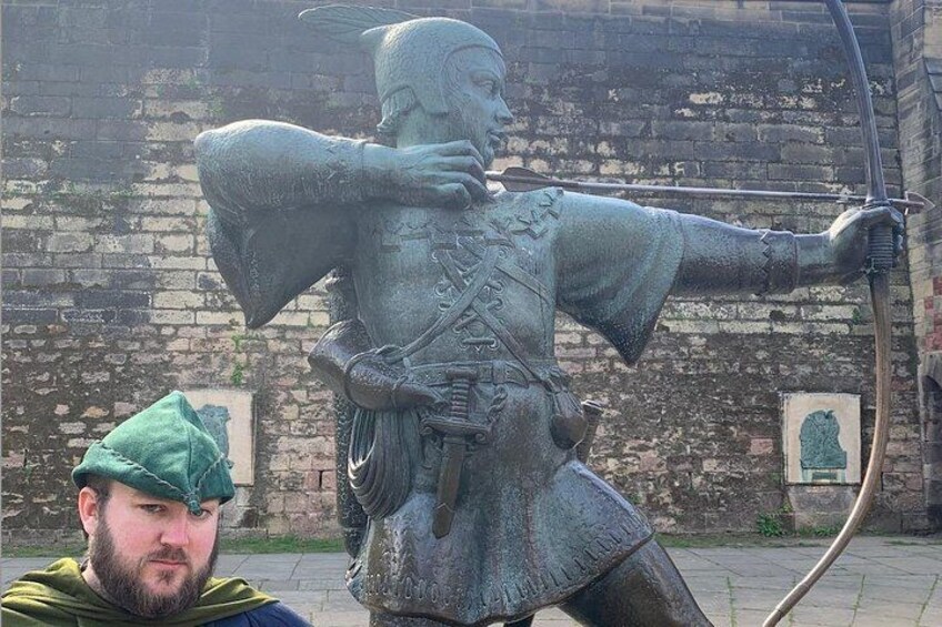 A bronze statue of a knight in armor holding a bow, with a brick wall in the background. 2