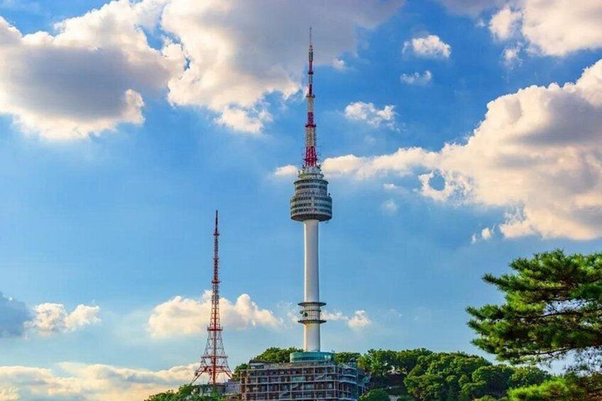A tall tower with a spire, surrounded by trees and a clear sky. 2