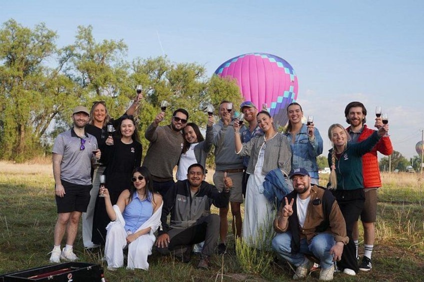 Een groep mensen buiten, met een luchtballon op de achtergrond. 1