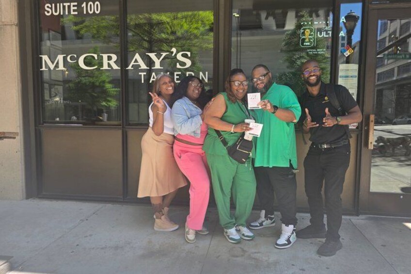 A group of people standing in front of a building with a sign that reads 'McCray's Tavern.' 2