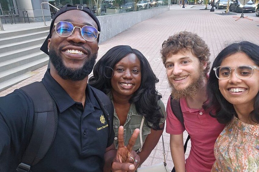A group of people taking a selfie on a city street with steps and buildings in the background. 3