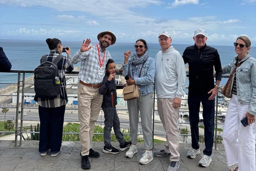 Un grupo de personas posando en un paseo marítimo con el océano al fondo. 1