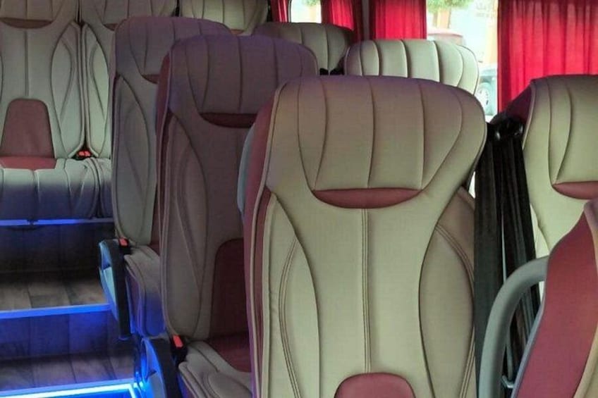 El interior de un vehículo con asientos de cuero color beige y detalles en rojo. 3