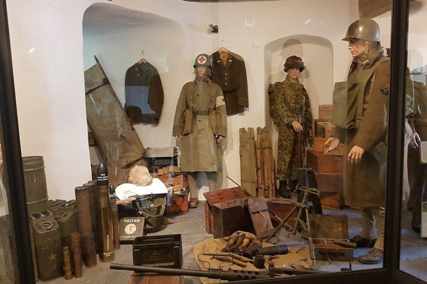 Una exhibición de museo con uniformes militares, cascos y artefactos históricos. 3