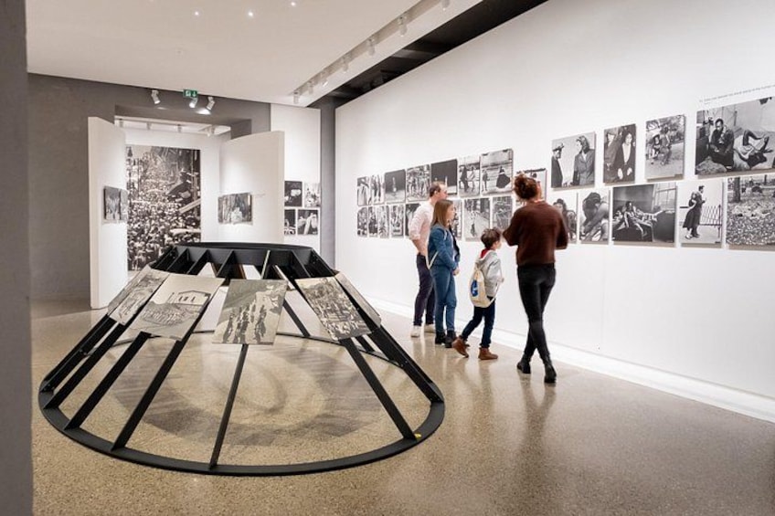 Una galería de arte con un espacio de exhibición central y fotografías en blanco y negro en las paredes. 4
