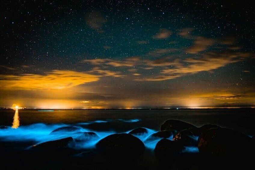 A night scene with a starry sky, a sunset reflecting on the water, and rocks in the foreground. 2