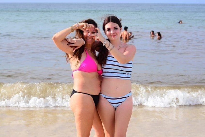 Zwei Personen stehen an einem Strand, im Hintergrund sind Wellen zu sehen. 1