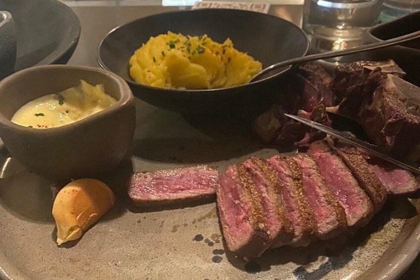 Un plato con bistec en rodajas, puré de papas y un tazón pequeño de salsa. 5