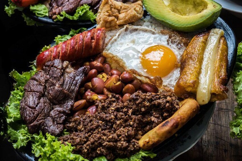 Un plato de comida con varios ingredientes, como un huevo frito, salchicha, frijoles y aguacate. 2