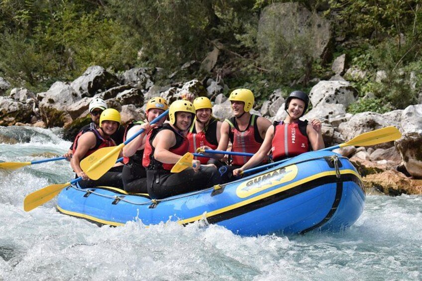 A group of people in a blue inflatable raft navigating a river with rapids. 5