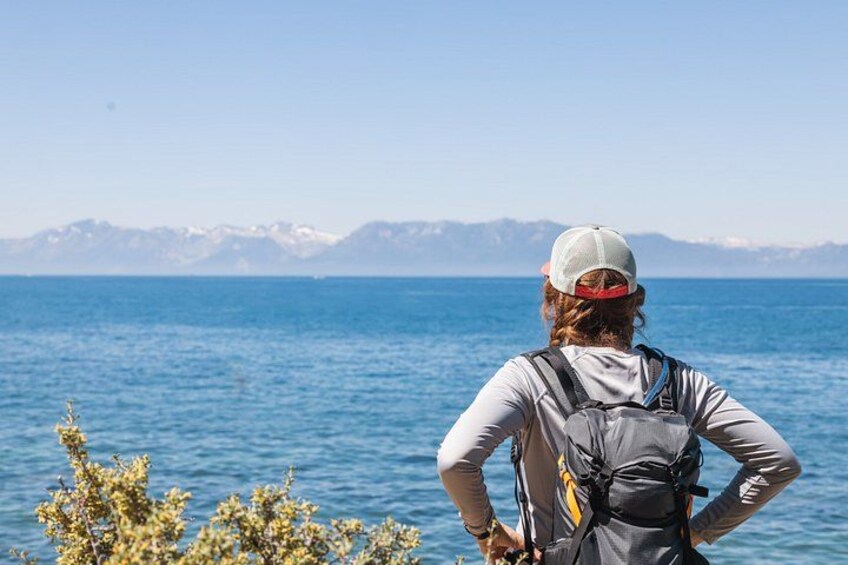Una persona in piedi vicino all'acqua, con montagne sullo sfondo. 1