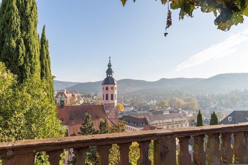 A town with a prominent clock tower, a bridge, and surrounding hills. 5
