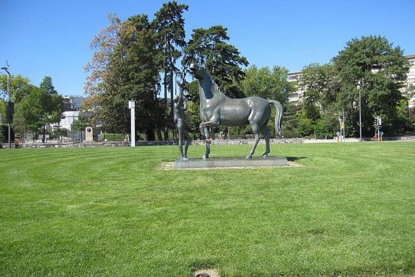 A large equestrian statue in a park with green grass, trees, and buildings in the background. 5
