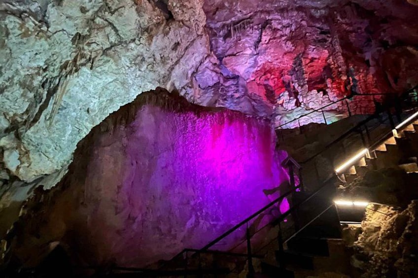 A cave with a purple light illuminating a large rock formation. 2