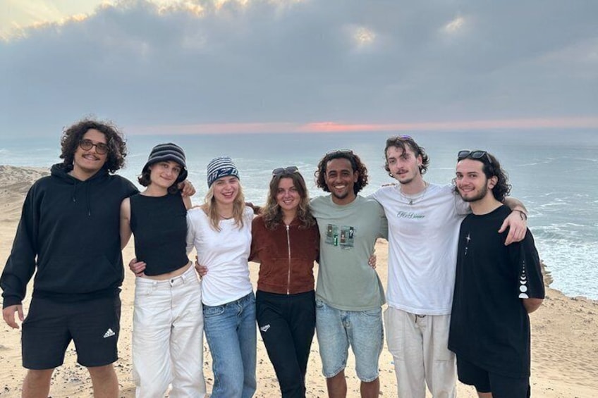 Un grupo de personas en la playa, con el océano y un cielo nublado al fondo. 5