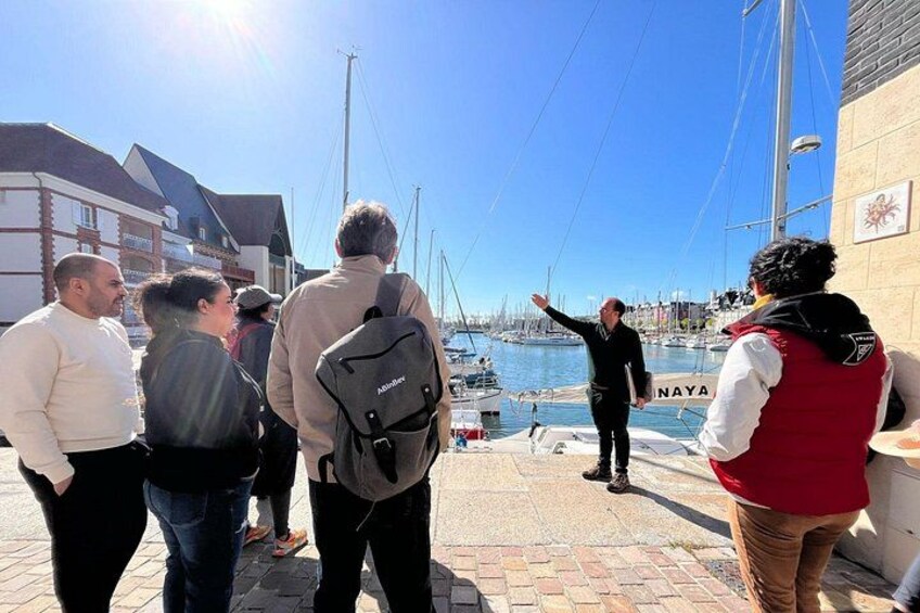 Un grupo de personas de pie en un muelle, con un puerto deportivo al fondo. 4
