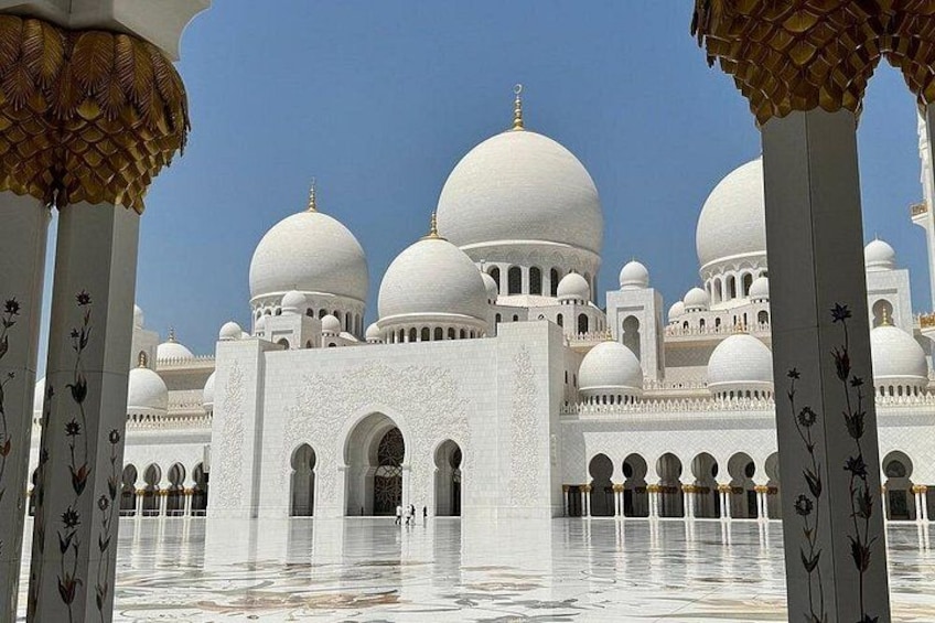 A white mosque with multiple domes and arched doorways. 1