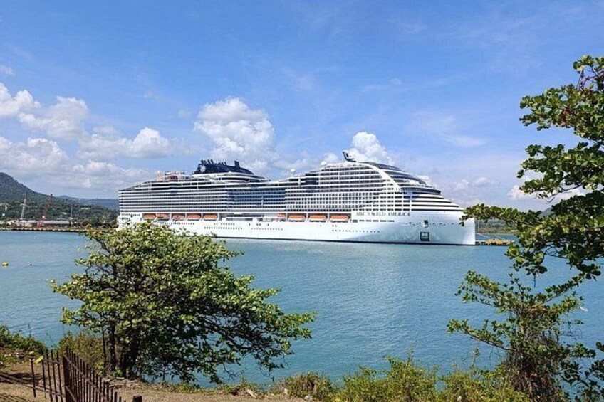 A large cruise ship docked at a port with clear skies and calm waters. 4