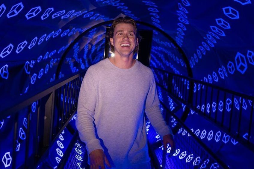 A person walking on a spiral staircase with illuminated geometric patterns. 2