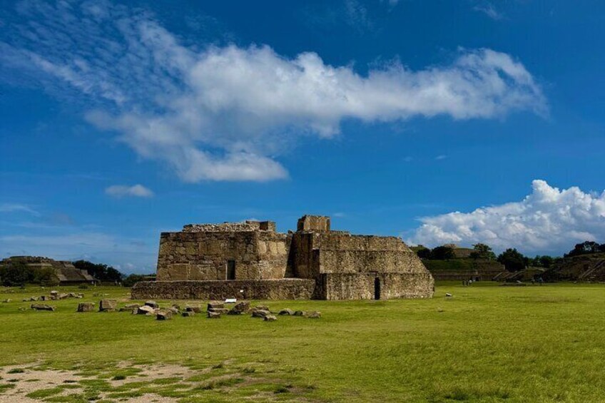 An ancient stone structure in a grassy field under a blue sky. 2