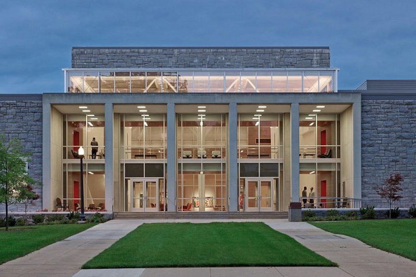 A modern building with a glass facade, a stone exterior, and a well-maintained lawn. 3