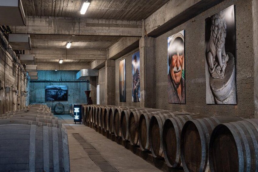 A wine cellar with wooden barrels, stone walls, and artwork. 4