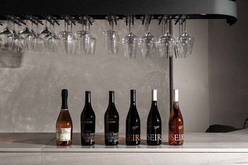 A row of wine bottles and glasses on a shelf. 5