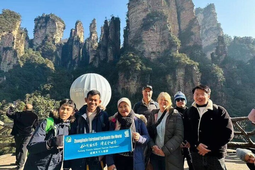 A group of people standing in front of a mountainous landscape with a sign that reads "Shanghai Fairyland Scenic Spot." 1