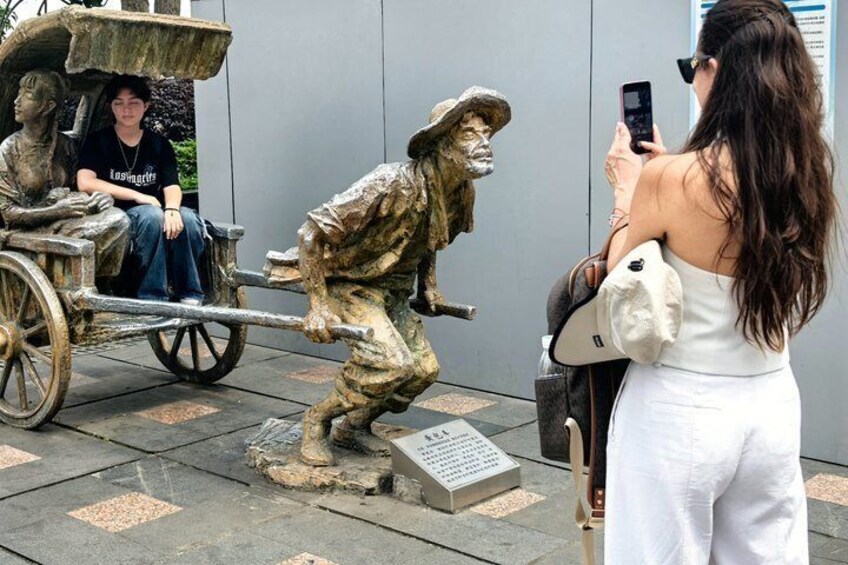 Een bronzen beeld van een man met een paard en wagen, een vrouw die een foto maakt, en nog een persoon zittend in de wagen. 4