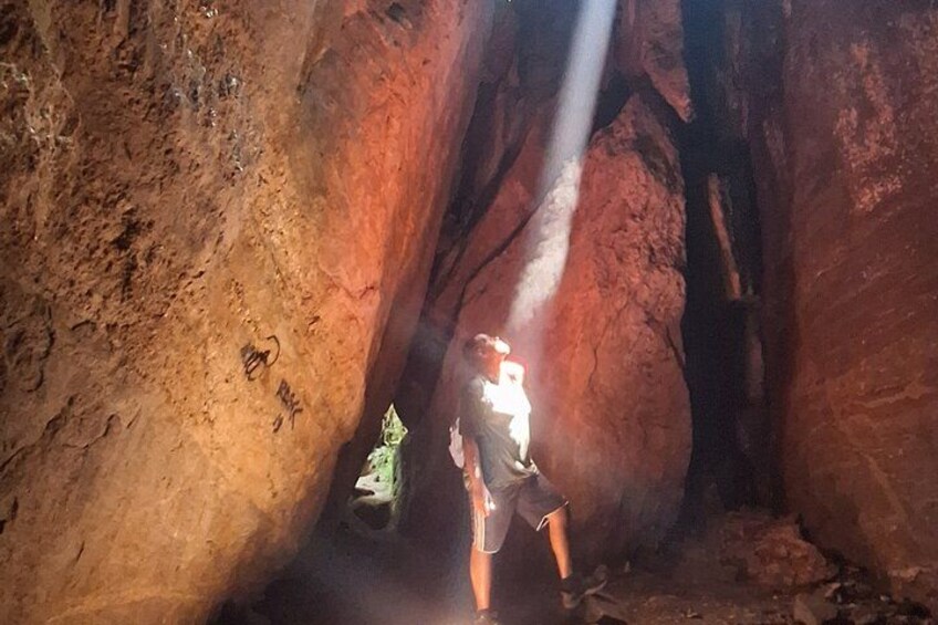 A person standing in a cave with a beam of light shining down. 3