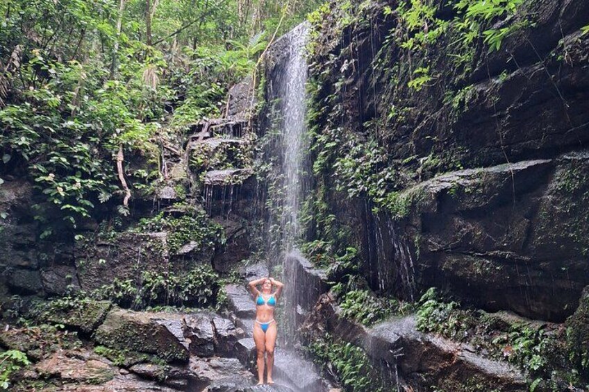 A waterfall in a forested area with a person standing near the water. 2