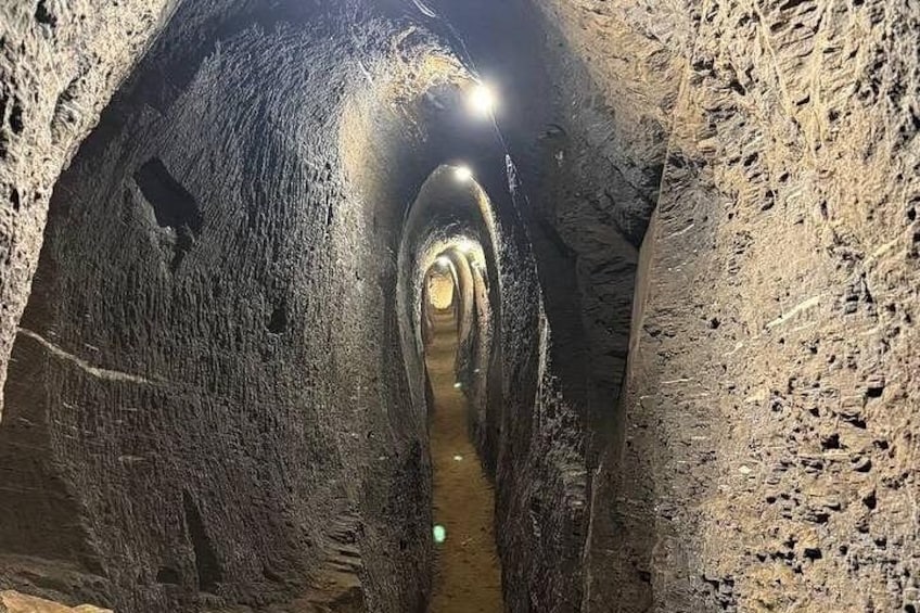 A narrow, illuminated tunnel with rough, textured walls. 2